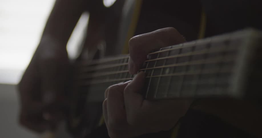 Person strums a guitar on a sunny day