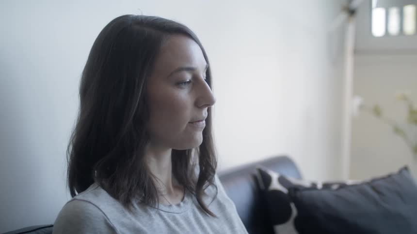 Woman sits on a couch on a sunny day