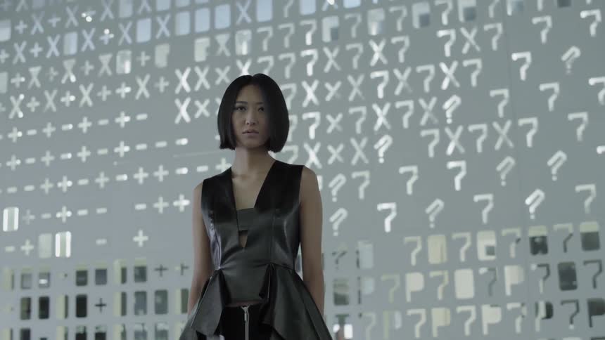 A woman stands in front of a wall of cutouts and lights