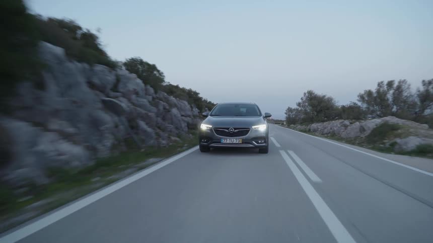 Car speeds down a country road at sunset