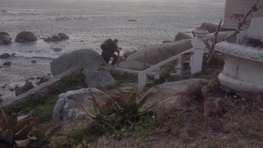 A man is crouching and taking photographs near the shore