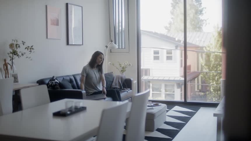 Woman sits on a couch and opens a laptop