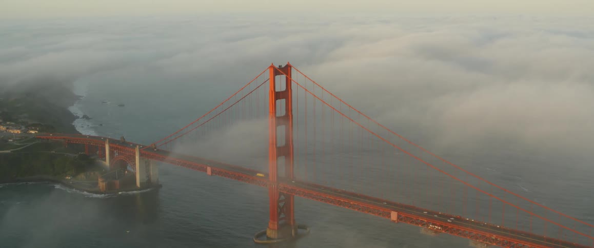 Fog rolling over a bridge and a body of water