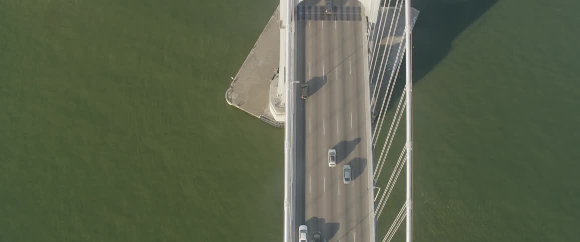 Several vehicles driving on a bridge over a large body of water