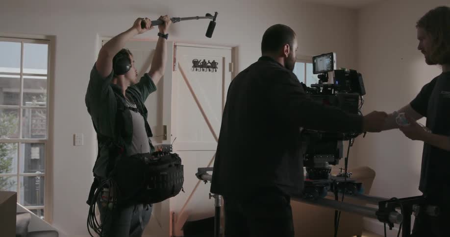 A film crew is filming an actor opening a door inside in daylight