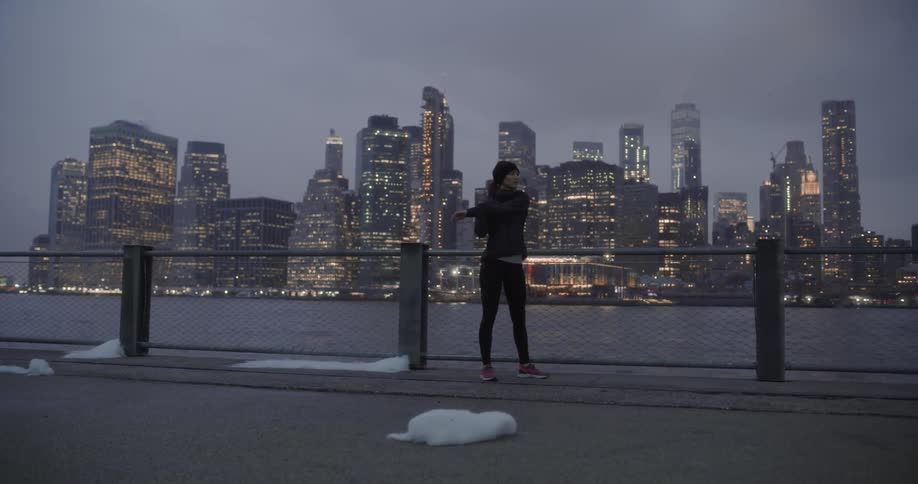 Woman stands by a fence near a river and takes off running