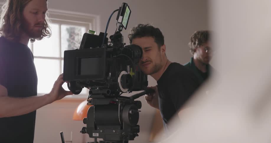 Man looks into a video camera as another man watches
