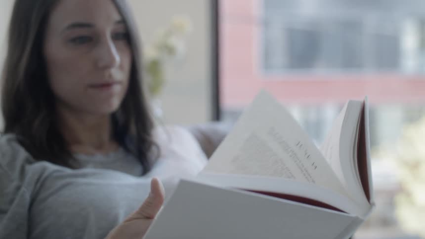 Woman sits on a couch reading a book
