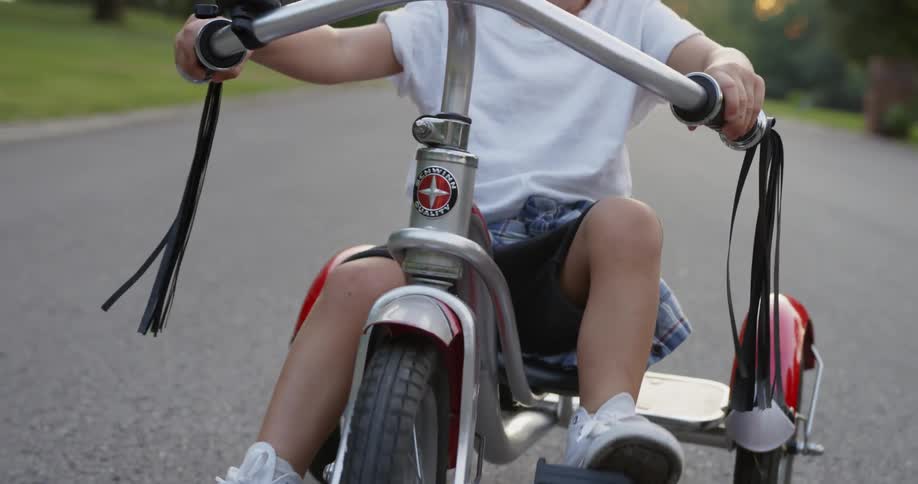 Child pedals a tricycle on a road