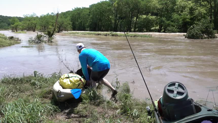 A man puts an oar on a packed canoe and grabs a bottle of water