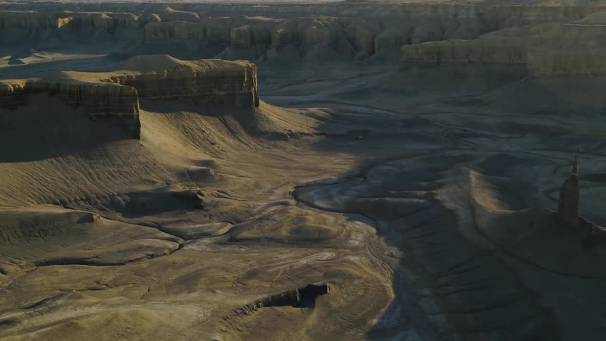 Shadows fall over a sandy desert with many plateaus