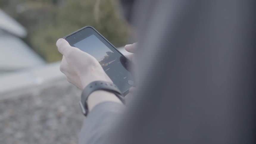 Person looks at phone while sitting outside