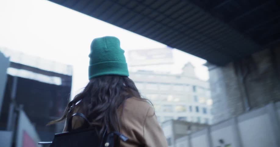 A woman walks under a city bridge