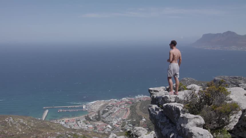 Man standing at the edge of a cliff overlooking a large body of water