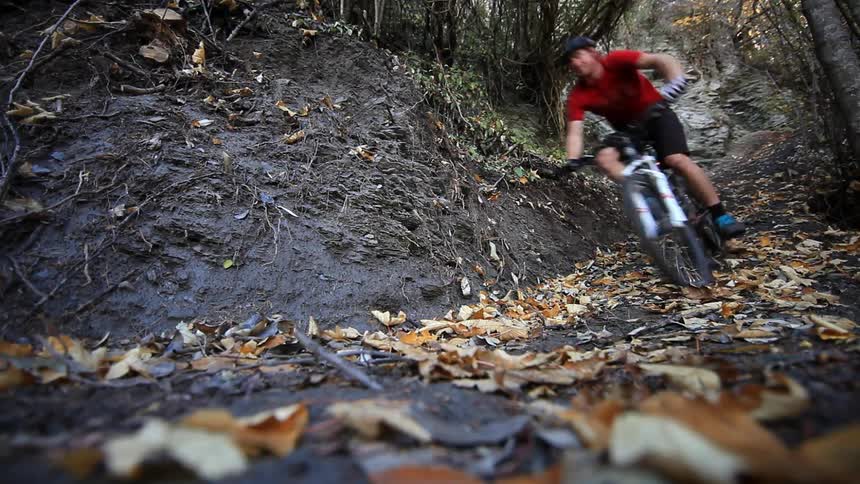 Man riding his mountain bike down a small trail downhill