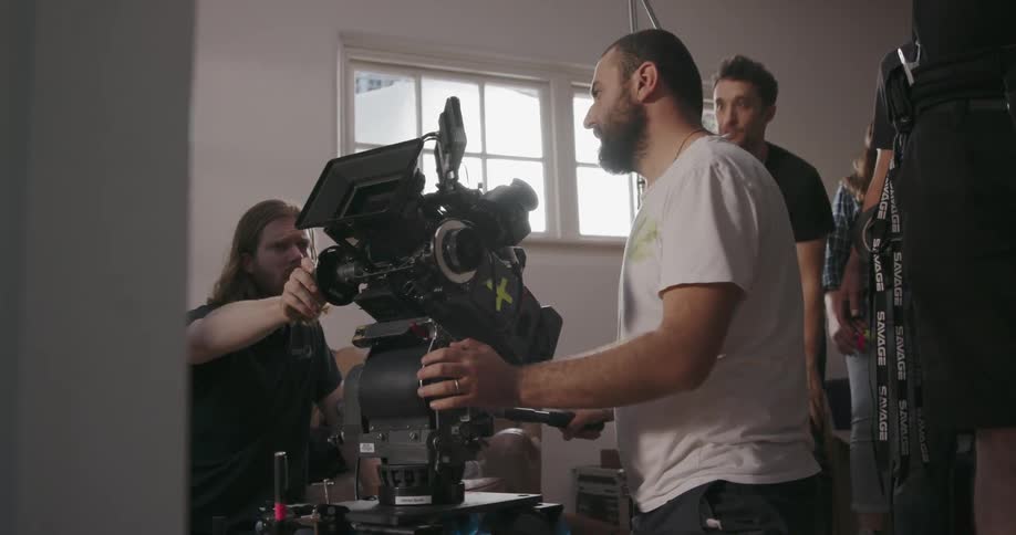 Men pushing a large camera in a house on a sunny day