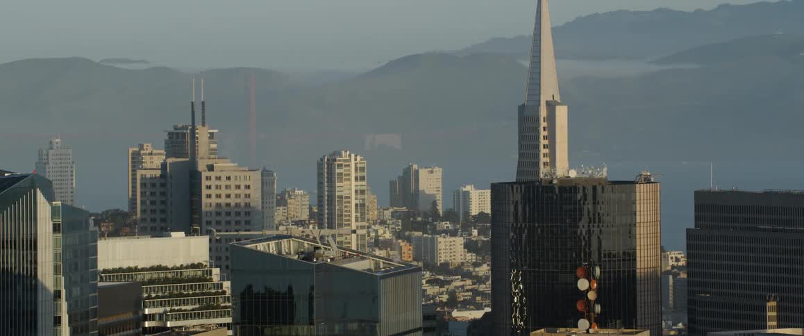 Sun shines over a large city near hilly landscape