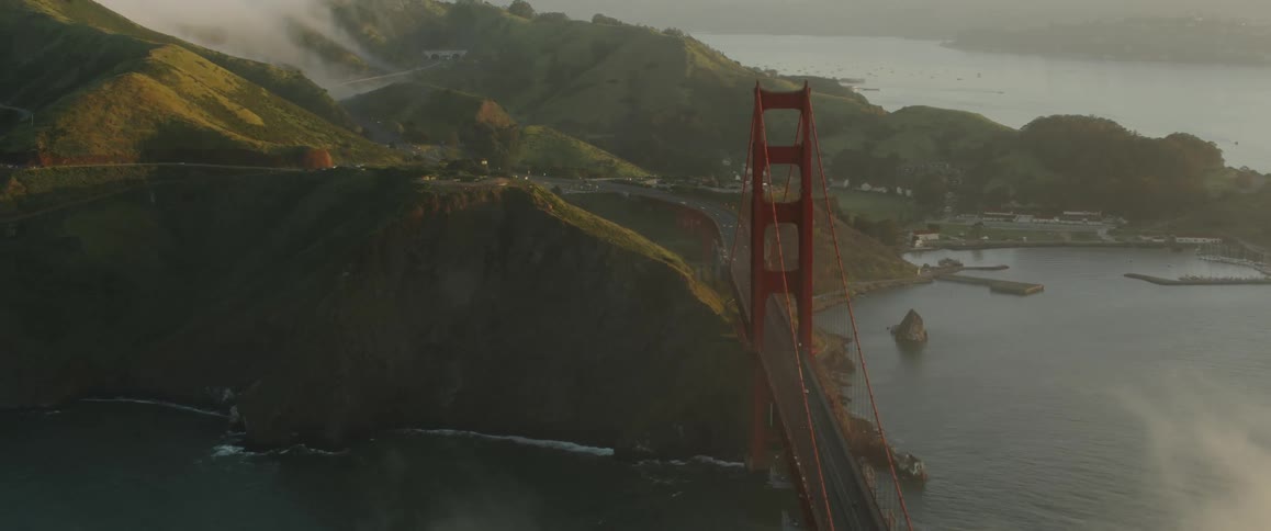 Clouds are drifting over the golden gate bridge and adjacent hills during the day