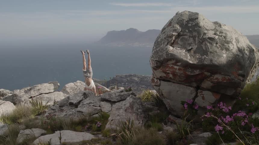 A person does a handstand near the cliff
