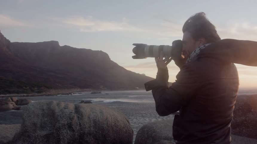 Man takes a picture with his camera outside at sunset