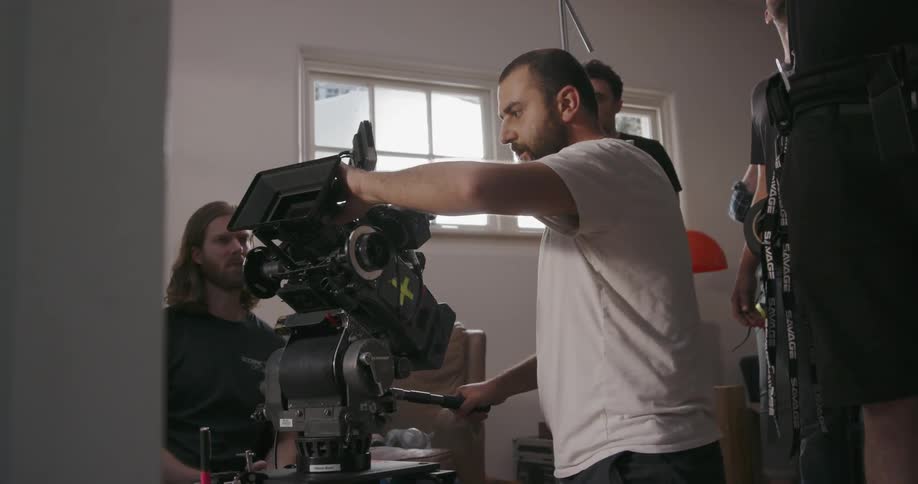 A man adjust a movie camera while others look on