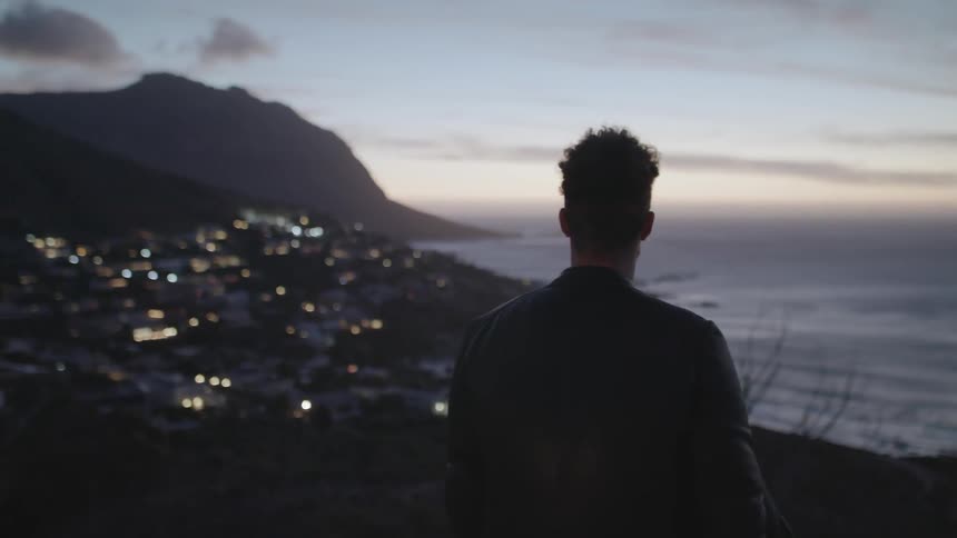 Man looks out over the ocean at dusk