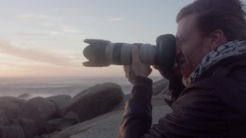 Man takes a photo with a camera then looks at the camera screen