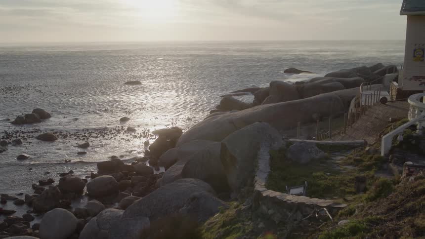 Sun shines over a rocky beach and flowing water
