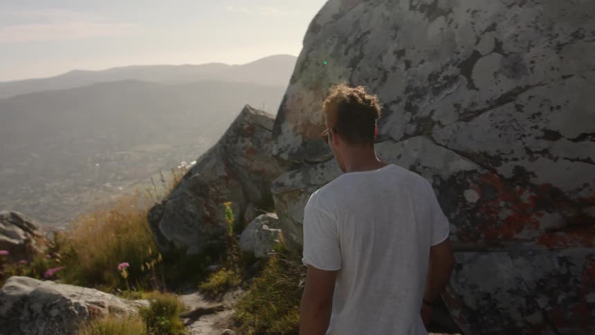 Man walks on rocky hilly terrain on a sunny day
