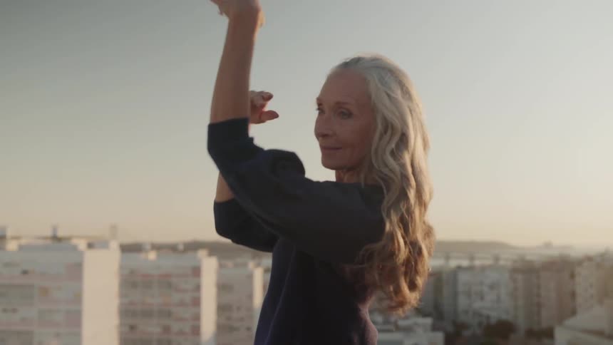 Woman dancing and waving her arms on a rooftop on a sunny day