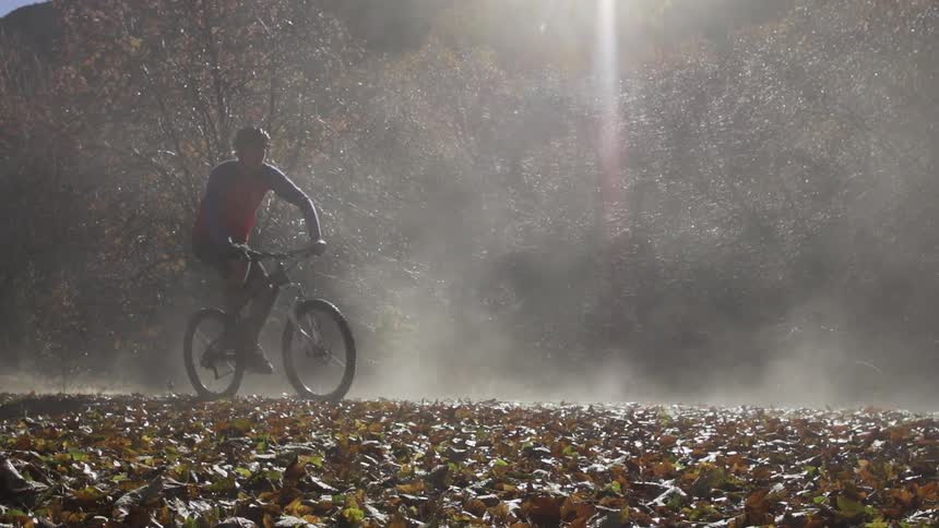 Man riding his bike over some autumn leaves