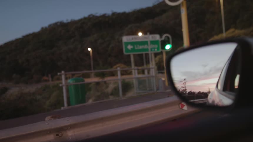 Traffic light shines green as a car sits nearby