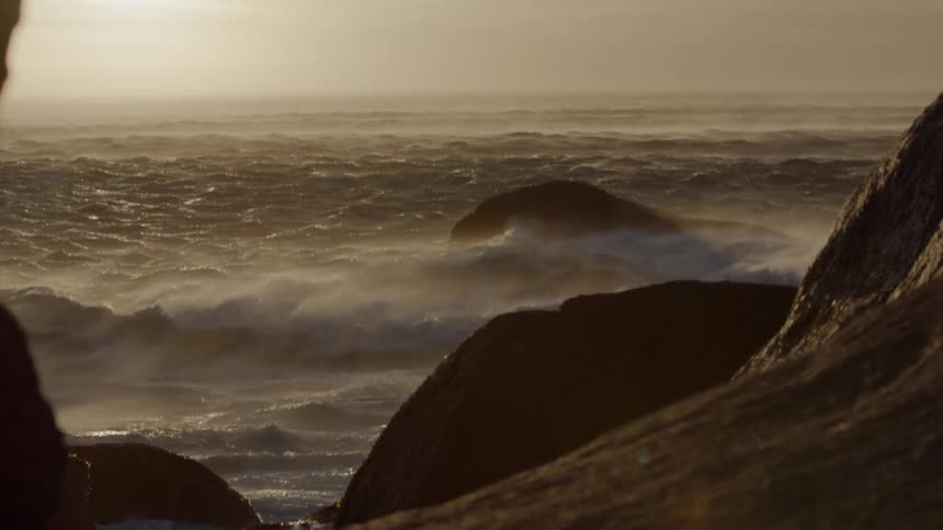 The wind is blowing the waves fast near the rocks