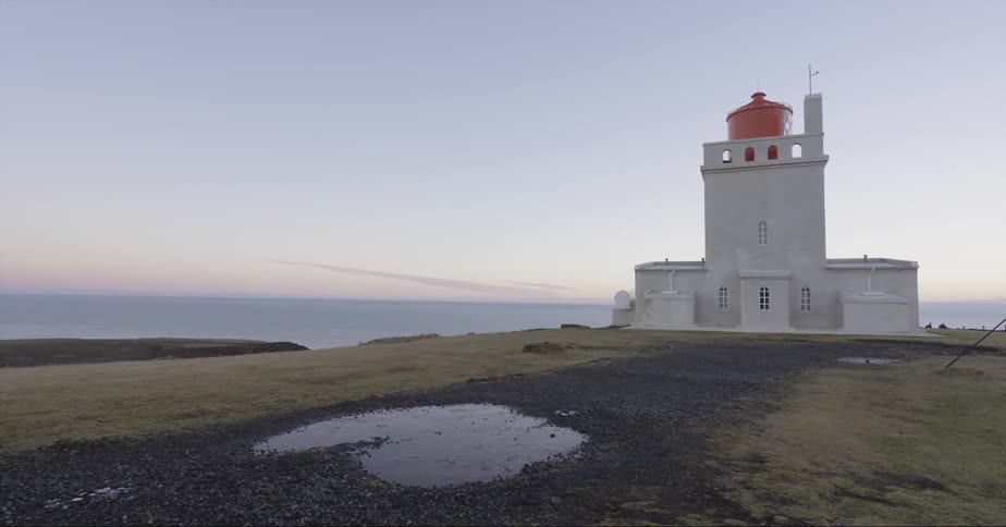 A lighthouse is standing guard atop a hill on a sunny day