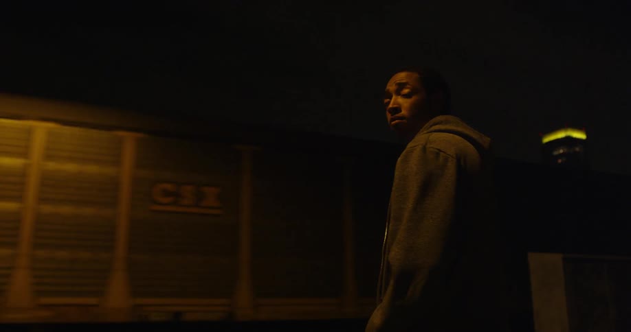 Person watching a train pass by in a city at night