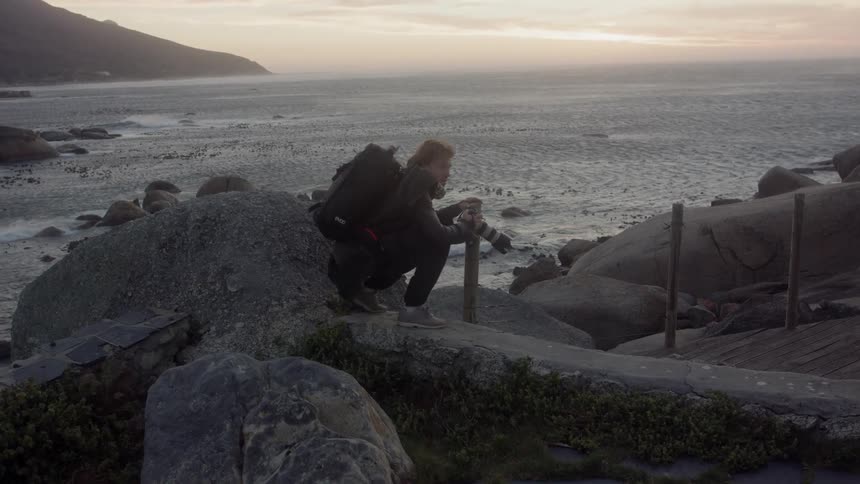 Man takes a picture with his camera outside at sunset