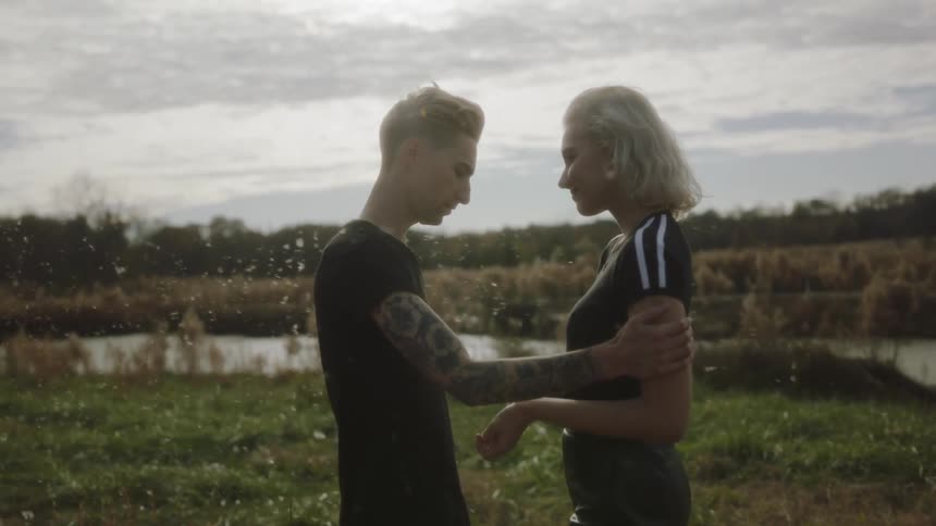 A man and woman stand together in a field