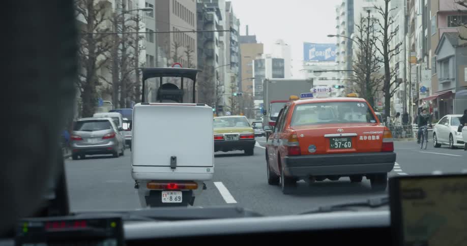 Many vehicles drive on a busy city street in Tokyo