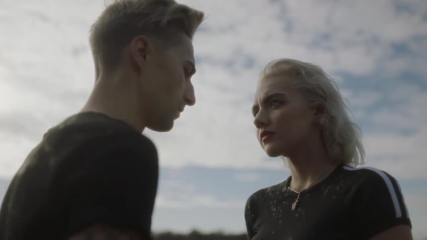 A man and woman are standing outside on a cloudy day looking at each other