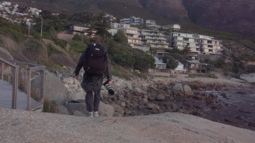 A man is carrying a camera over to the water