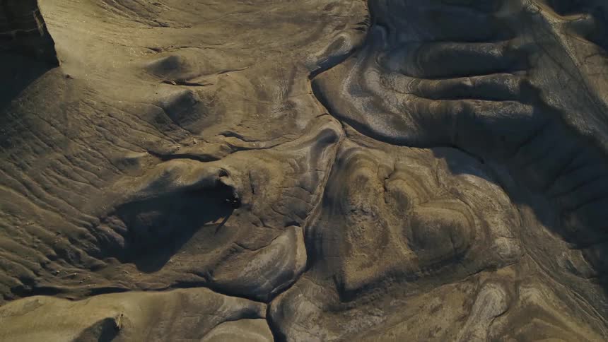 The traces of a dry river mark a canyon floor in daylight
