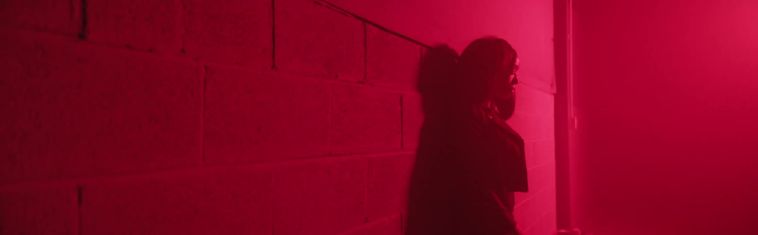 A woman leans against the the wall in the dark
