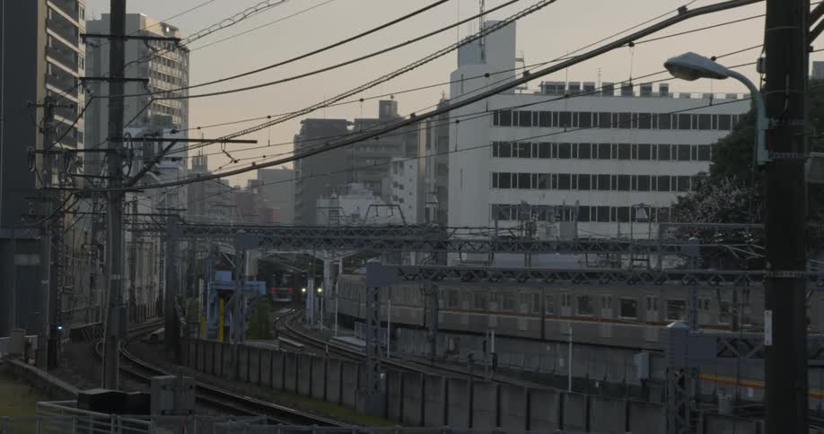 A commuter train is traveling on a track in Tokyo at dawn