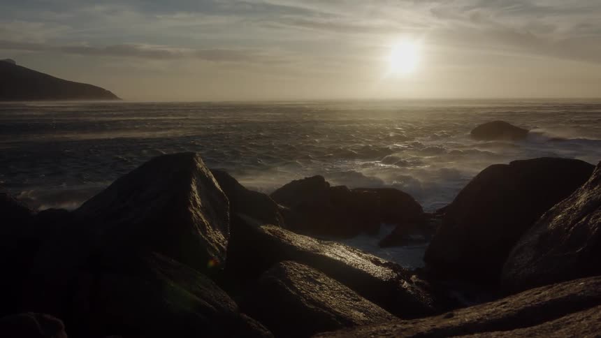 The sun is beginning to set on the rough coast line