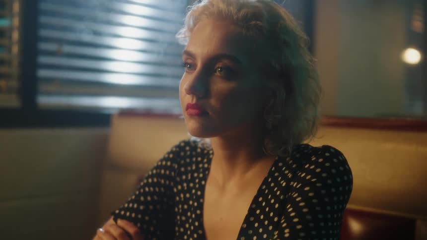 A woman sits in a diner booth at night