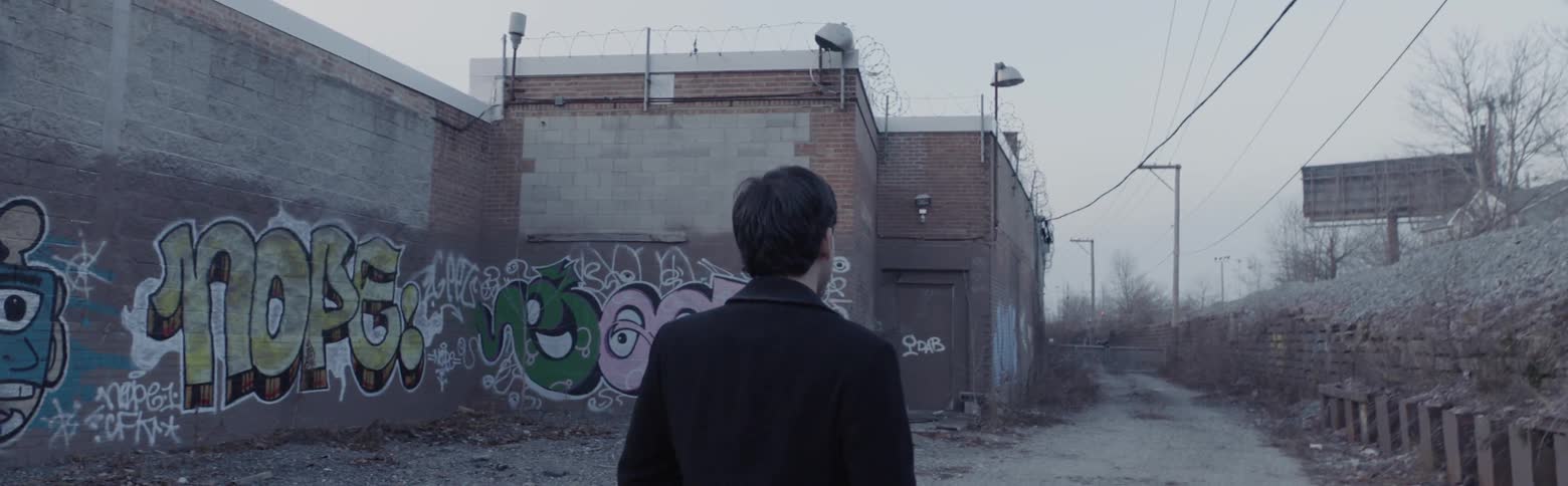 A man walks down a graffiti filled alley