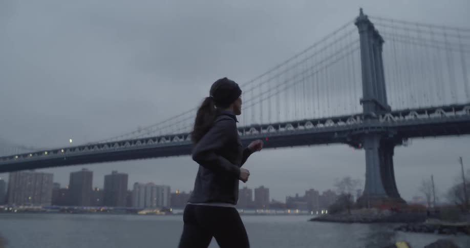 A woman jogs by the bridge on a cloudy day