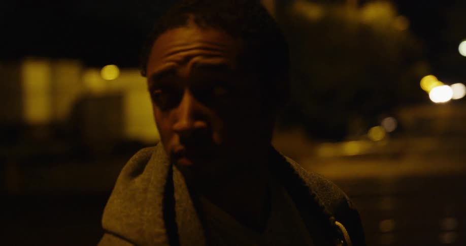 Man looks around walking in a city at night