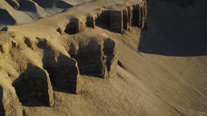 Sand and silt pile up at the base of canyon walls on a sunny day
