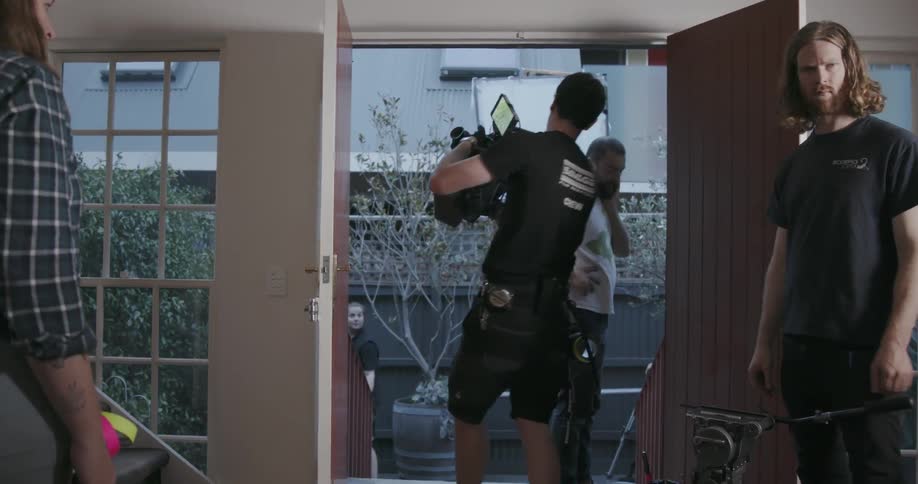 Man carries a video camera through the doorway and outside
